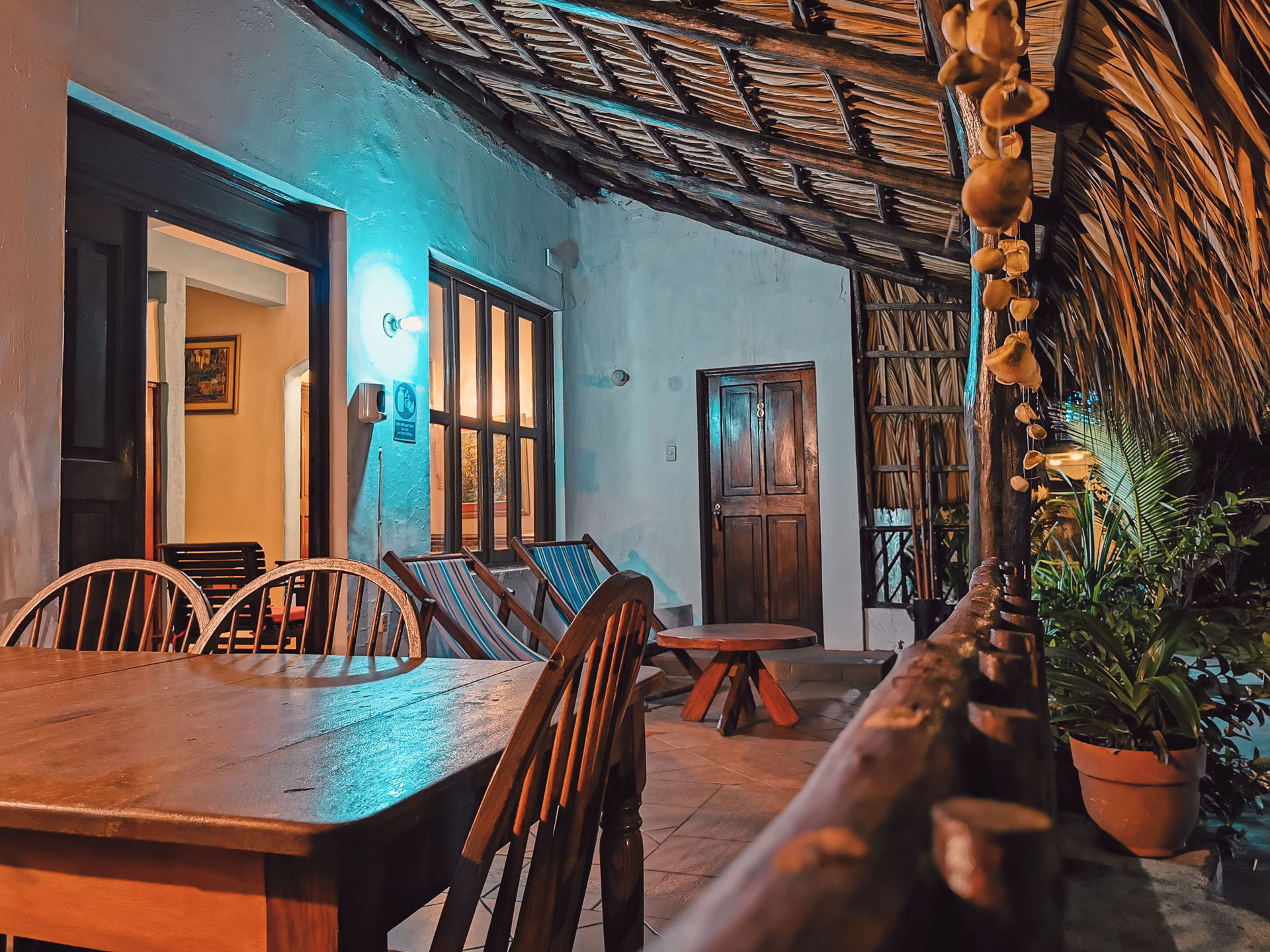 Terraza común con mobiliario de madera y techo de palma